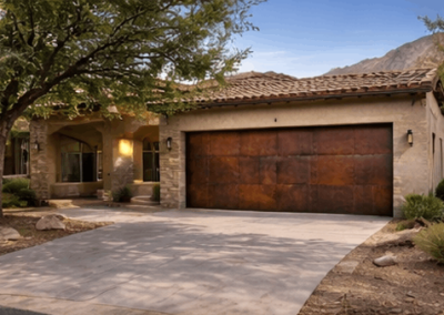 Weathered-iron style garage door on a stone home with mountains behind it